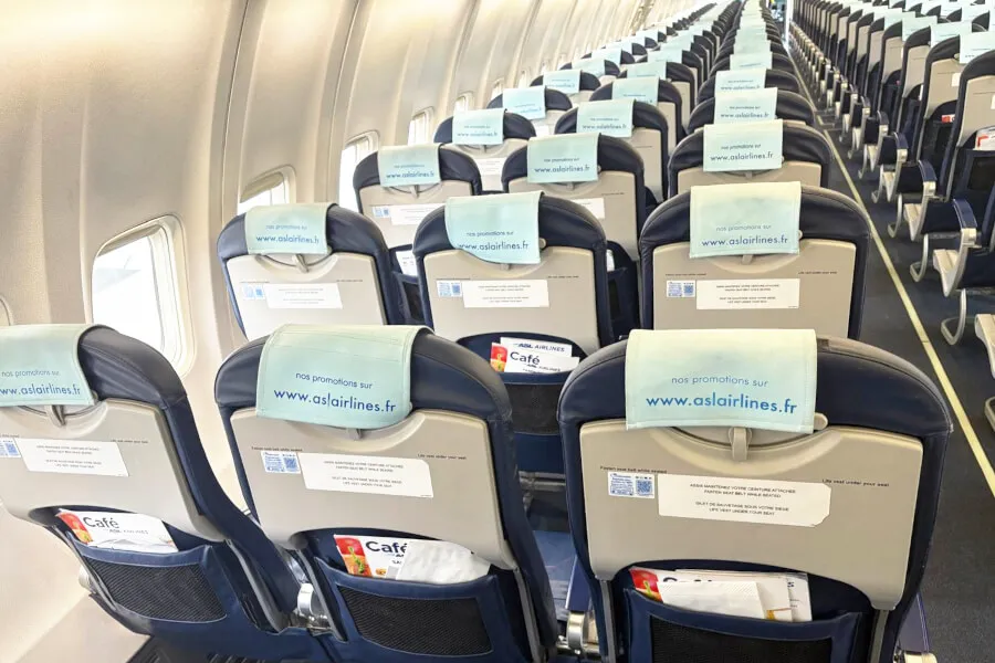 Interior of airplane with seatback advertisements.