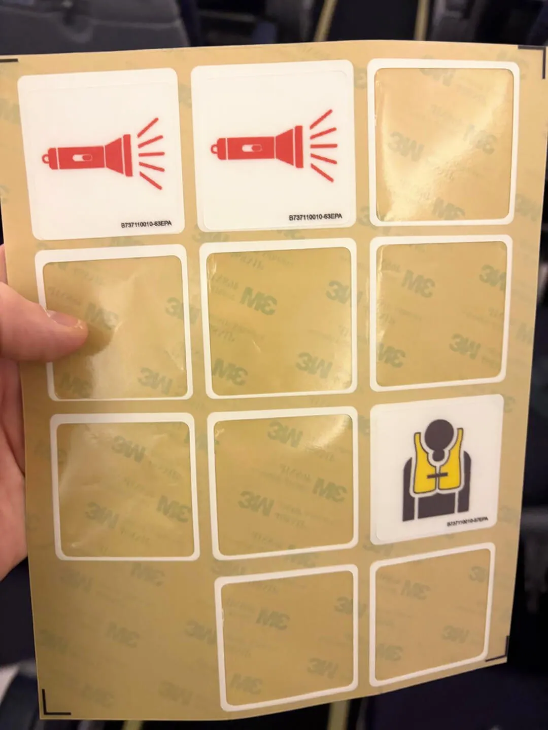 Airplane safety stickers: flashlight and life vest symbols.